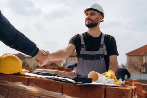 Is Roofing Business Profitable? 8 Roofer shaking hands on a construction site deal while discussing the question is roofing business profitable.